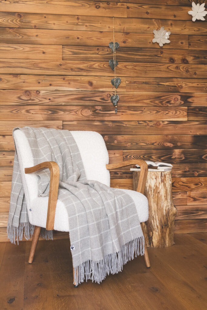 Plaid CAMILLE à carreaux posé sur un fauteuil blanc